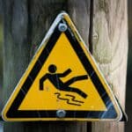 Yellow triangle warning sign with a black graphic of a person falling. Slip, trips, and falls.